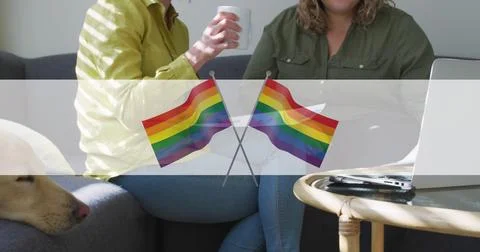 Image of rainbow flags over midsection of lesbian couple drinking coffee Fotos Stock