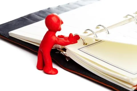 Image of red plasticine man turning over the pages Stock Photos