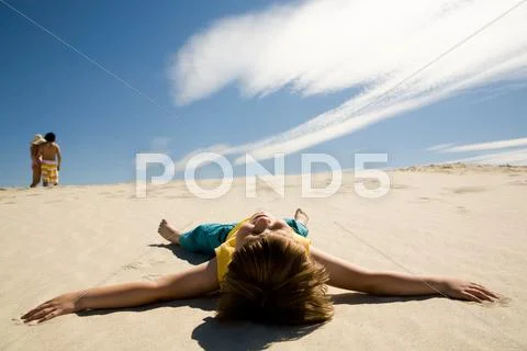 Image of restful boy lying on sand under blue sky and enjoying sunny day Stock Photos