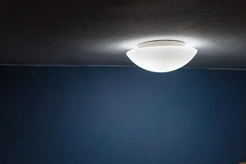 Image of a room corner with a lit circular ceiling light fixture casting ligh Stock Photos