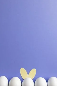 Image of row of white easter eggs with bunny ears and copy space on purple 스톡 사진