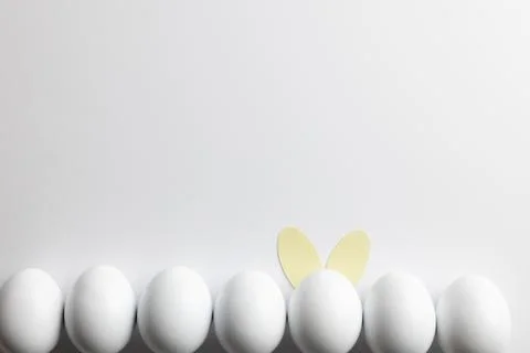 Image of row of white easter eggs with bunny ears and copy space on white 库存照片