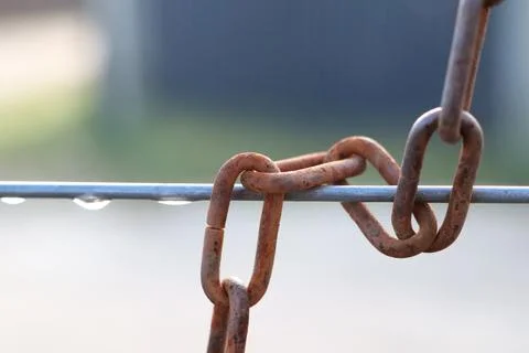 This is an image of a rusty chain link hanging on a metal wire adorned with Stock Photos