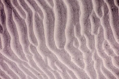 The image is of a sandy beach with a pattern of waves and ripples Foto stock