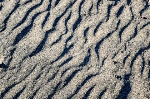 The image is of a sandy beach with a pattern of waves and ripples Foto stock