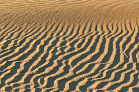 The image is of a sandy beach with a pattern of waves and ripples Stock Photos