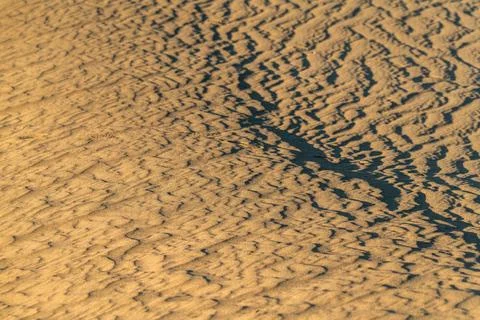 The image is of a sandy beach with a pattern of waves and ripples Stock Photos