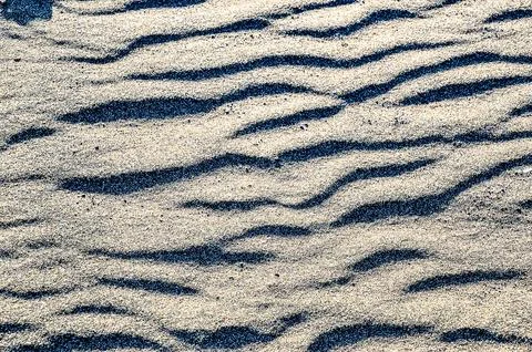 The image is of a sandy beach with a zigzag pattern in the sand Stock Photos