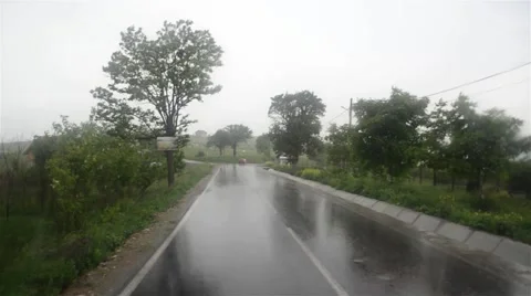 Image seen through the windshield of a car that goes on a paved road drenched Stock Footage 61781757