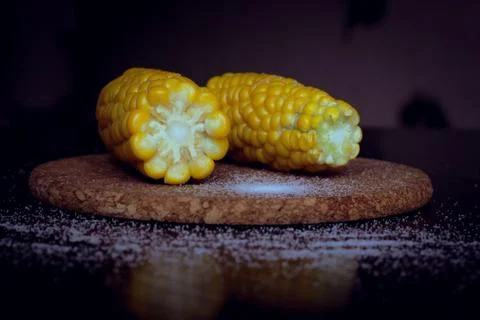 Image with selective focus.two corn cobs sprinkled with salt on a platter Stock Photos