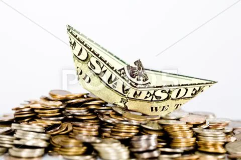 Image of ship made of dollar above a lot of coins Stock Photos