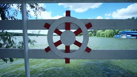 Image of a ship steering wheel on a fence near a river Stock Footage 123712805