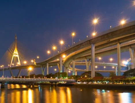 Image showcases stunning view of modern bridge illuminated at night, reflecti Stock Photos