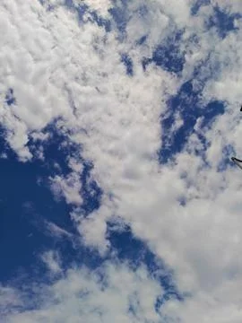 An image showcasing a deep blue sky partially covered by a variety of white f Stock Photos