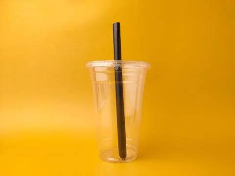 The image shows a clear disposable plastic cup with a lid and a black straw.. Stock Photos