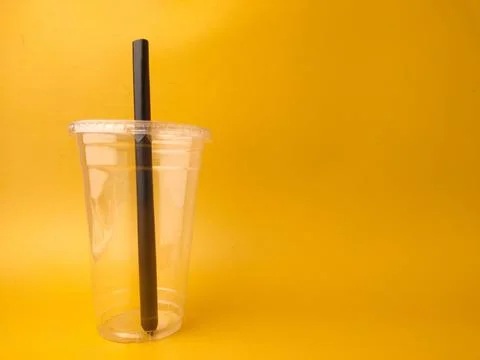 The image shows a clear disposable plastic cup with a lid and a black straw.. Stock Photos