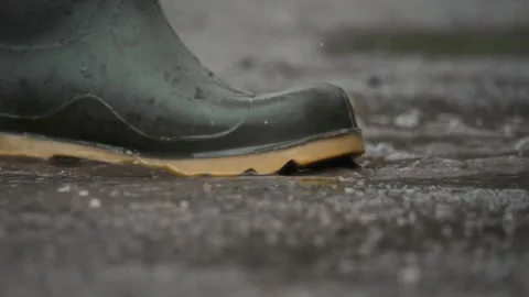 This image shows a closeup of waterproof boots splashing through rain puddles Stock Footage 313283536
