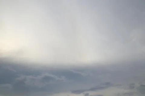 The image shows a cloudy sky with a mix of light and dark gray hues. The over Stock Photos
