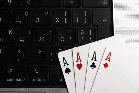 Image shows a deck of playing cards and a laptop keyboard, representing gam.. Stock Photos