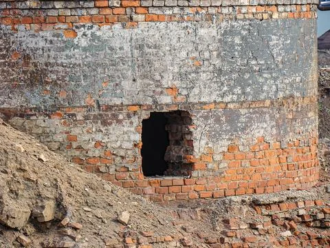 The image shows a dilapidated brick structure with an arched opening, possi.. Stock Photos