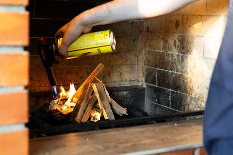 This image shows a fireplace being lit using a butane torch. The flame from t Stock Photos