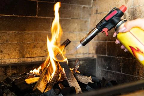 This image shows a fireplace being lit using a butane torch. The flame from t Foto stock