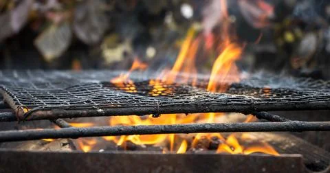 The image shows a grill with flames burning under the grates. The grill appea Stock-Fotos