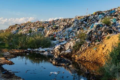 The image shows a massive pile of garbage next to a polluted pond. 库存照片