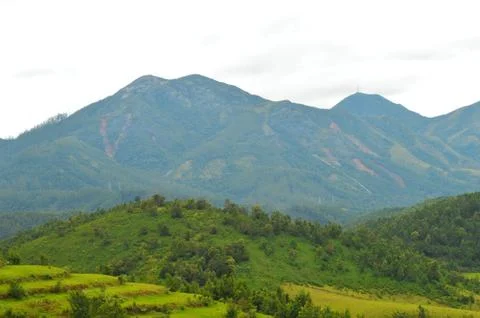 The image shows mountains in a distance with multiple landslides. During rain Stock Photos
