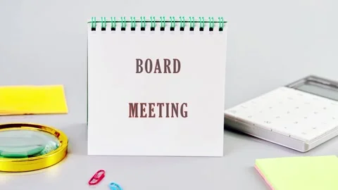 The image shows a notepad with Board Meeting written on it. Various items such Stock Footage 327360457