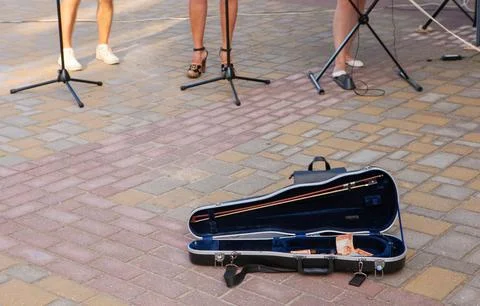 The image shows an open violin case on the ground near the musicians. There i Stock Photos