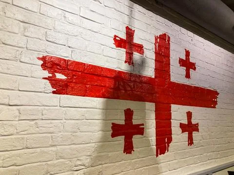 Image shows a peeling red cross on a brick wall, with shadow cast on lower .. Stock Photos