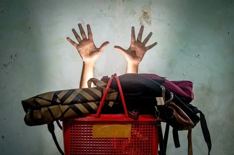 The image shows a red basket filled with bags, with two hands reaching up f.. 스톡 사진
