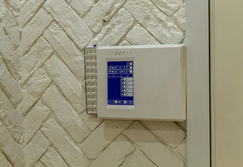 The image shows a security control panel mounted on a textured white wall. .. Stock Photos