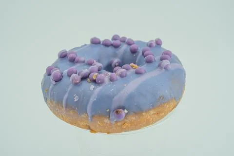Image shows a single round doughnut with lavender icing, artistically swirled Stock Photos