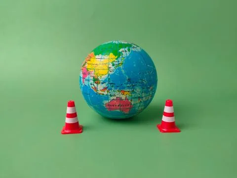 The image shows a small globe placed between two miniature red-and-white tr.. Stock Photos