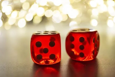 Image shows two red dice with black dots against a warm, festive backdrop I.. Stock Photos