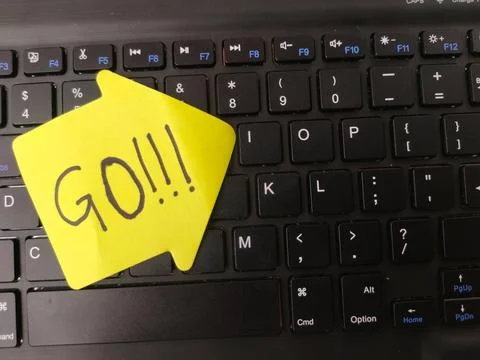 The image shows a yellow, arrow-shaped sticky note with the word GO!!!writt.. Stock Photos
