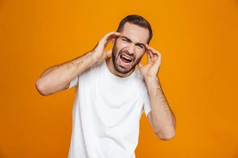 Image of sick guy 30s in t-shirt screaming and rubbing temples because of hea Stock-Fotos