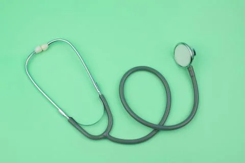 A image of single normal stethoscope isolated on top of a green color paper b Stock Photos