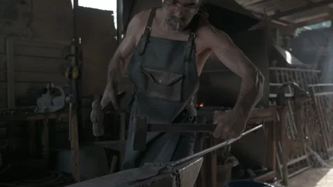 Image of a skilled craftsman, bearded and in an apron, shaping iron with pr.. Stock Footage 253201329
