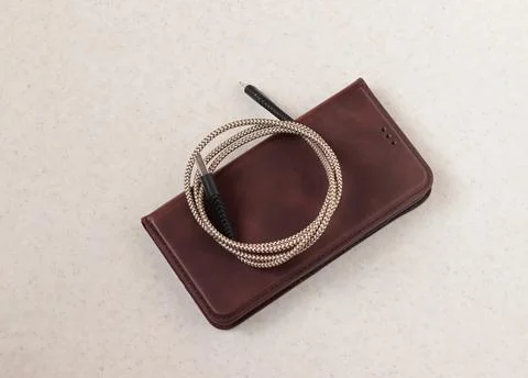 Image of a smartphone in a case on which the charging cord is folded into a.. Stock Photos