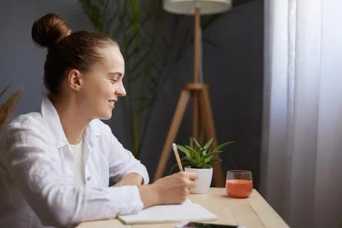 Image of smiling positive optimistic young beautiful woman writing down not.. Stock Photos