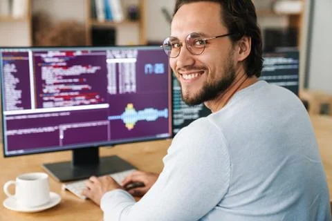 Image of smiling unshaven programmer man working with computers Stock Photos