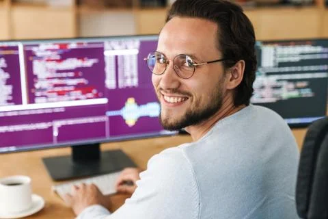Image of smiling unshaven programmer man working with computers Stock Photos