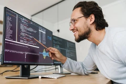 Image of smiling unshaven programmer man working with computers Stock Photos