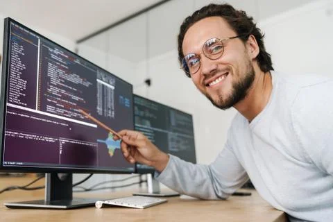 Image of smiling unshaven programmer man working with computers Fotos de archivo