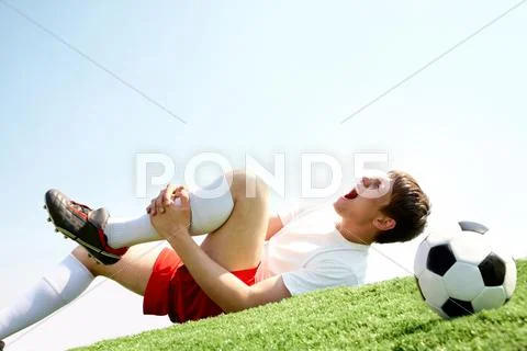 Image of soccer player lying down and shouting in pain Stock Photos