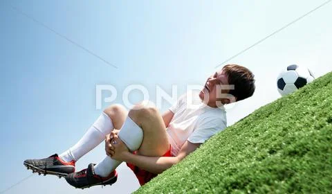 Image of soccer player lying down and shouting in pain Stock Photos