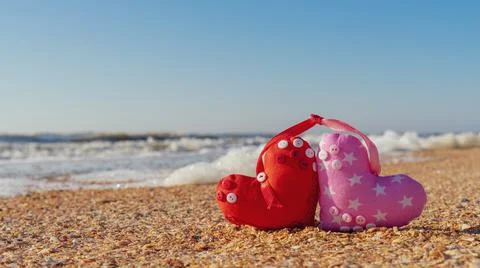 Image of a soft toy in the shape of a heart on the beach. Stock Photos